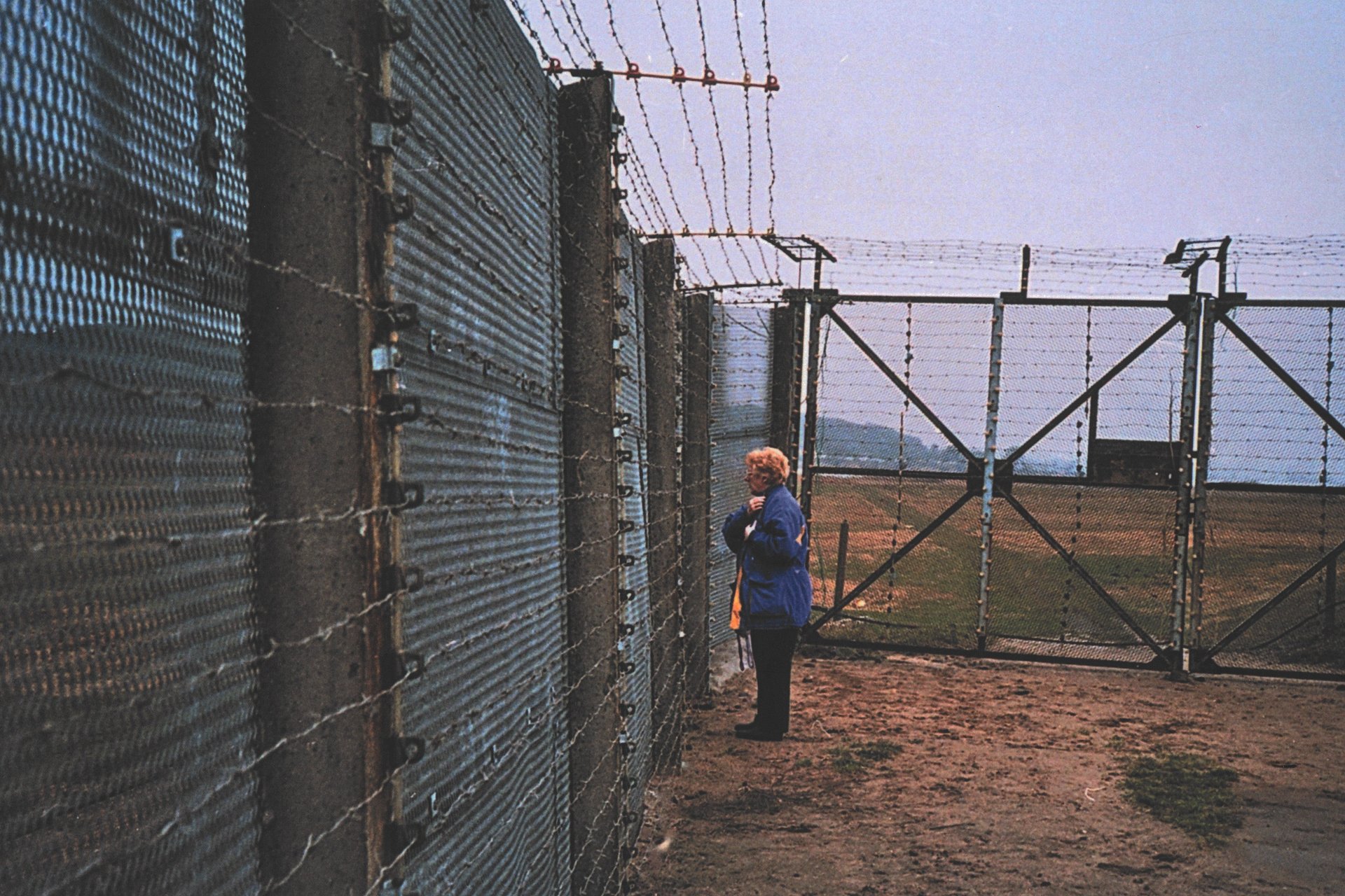 Eine Frau steht vor der Grenzanlage, die die BRD von der DDR trennte. Foto: Hans-Joachim Hahn